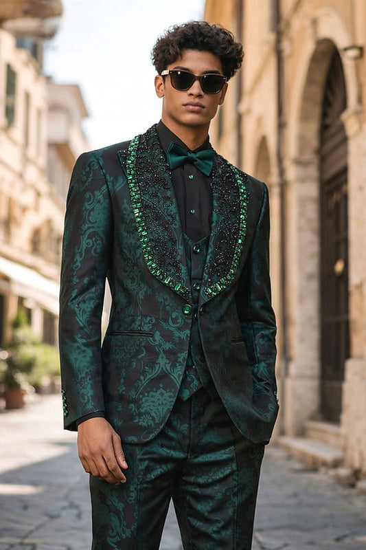 A man wearing the Manzini Aspen 3-Piece Slim-Fit Men's Fancy Rhinestone Woven Pattern Tuxedo in hunter green and sunglasses stands on a cobblestone street lined with buildings.