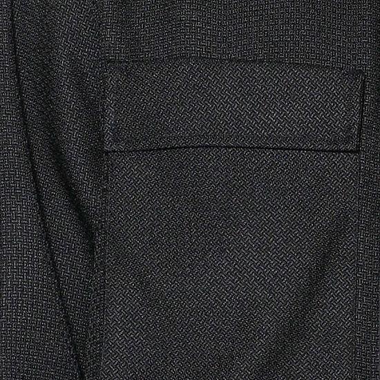 A man faces forward in the Insomnia Cavalli 2PC Black Leisure Suit by Insomnia, featuring a black button-up shirt with front pockets and matching pants, set against a light-colored, ornate wall background.