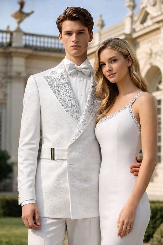 A man wearing the MANZINI MZS-607 Double Breast Slim-Fit Coat with a shiny rhinestone floral pattern stands outdoors with a woman in a white dress, in front of an ornate building.