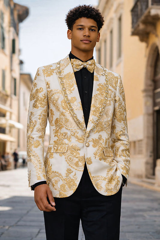 A man stands outdoors wearing the Manzini MANZINI MZS-602 Men's Rhinestone Shiny Metallic Floral Tuxedo Prom Jacket in champagne, paired with a matching bow tie, black shirt, and black pants. One hand is in his pocket.