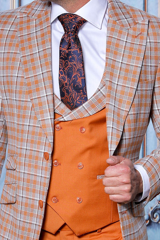 A man in the Insomnia INSOMNIA PARIS-6 3-Piece Tailored Fit Plaid Formal Business Rust Suit stands before an ornate blue wall, wearing a plaid jacket, double-breasted vest, rust pants, white shirt, and patterned tie.