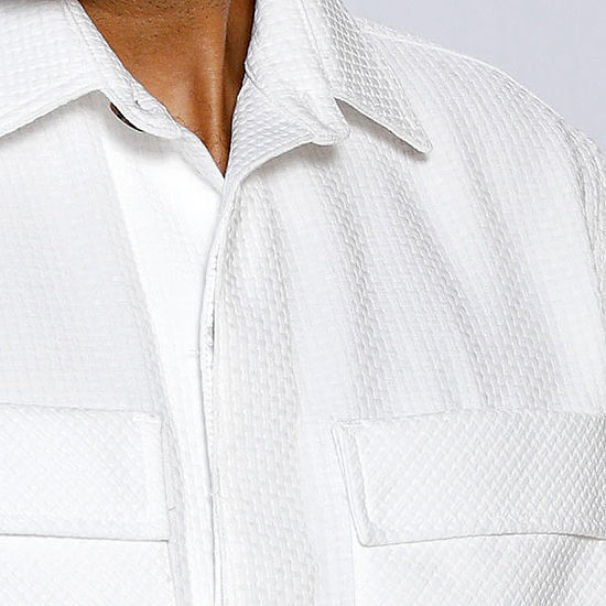 A man with short hair and a beard wears the INSOMNIA ROBERTO 2PC White Leisure Suit by Insomnia, standing against an ornate light-colored wall.