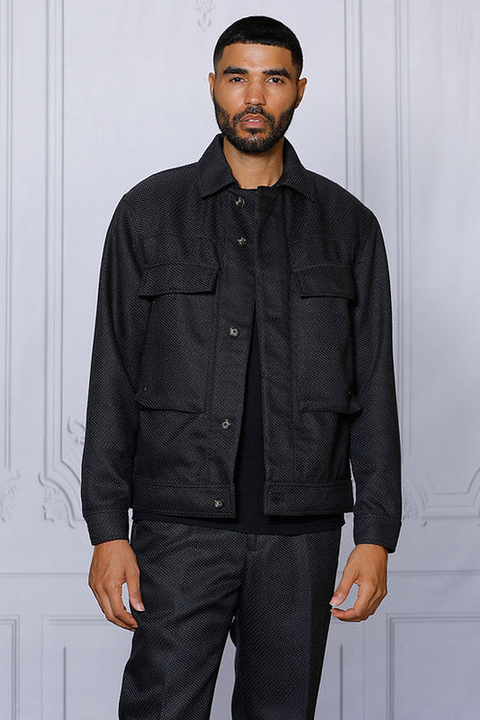 A man stands against a light-colored, paneled wall wearing the Insomnia INSOMNIA FENDI 2PC Black Leisure Suit.