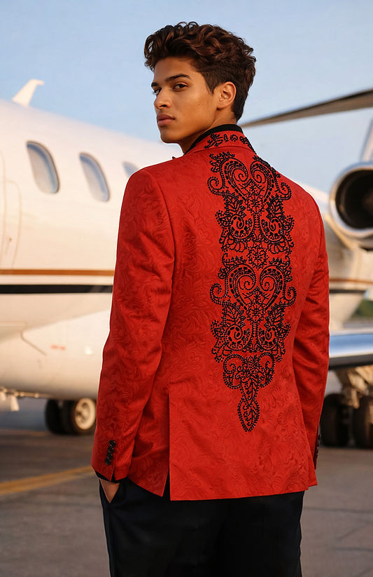 A man in a Manzini MANZINI MZS-606 Double Breast Slim-Fit Coat with shiny rhinestone red and black floral pattern stands in front of a private jet on an airport tarmac.
