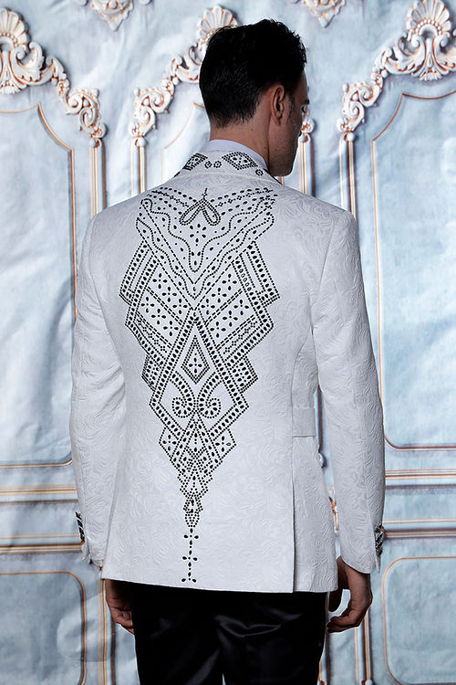 Man in a MANZINI MZS-603 Fancy Shiny Rhinestone Floral Pattern White/Black Jacket by Manzini, standing against a decorative wall.