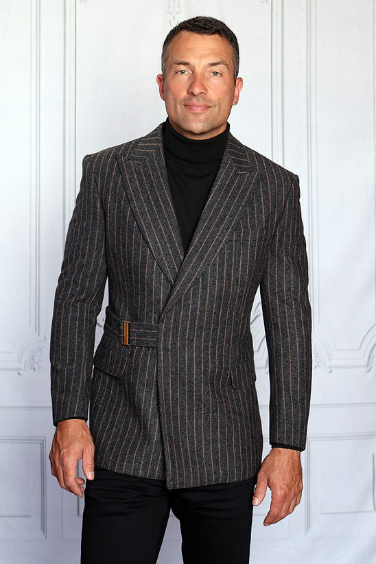 A man wearing the Manzini MANZINI MZW-702 Men's Pinstripe Blazer Coat w/ Hook Belt in charcoal over a black turtleneck, shown from the shoulders up against a light background.