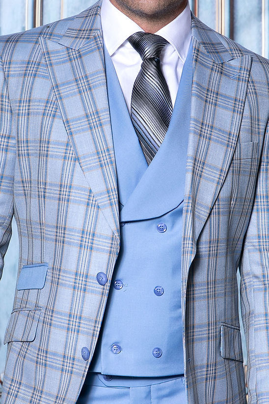 A man wears a MANZINI PARIS-4 Men's 3-Piece Tailored-Fit Plaid Business Suit in sapphire by Manzini, featuring a light blue vest and pants, standing before an ornate decorative background.