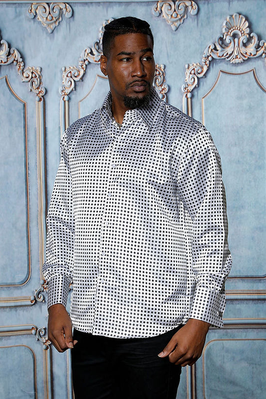 A man wearing a Manzini MZT-164 Small Polka Dot White Long Sleeve Satin Shirt with cuff and link stands in front of a blue and gold decorative background, looking to the side.