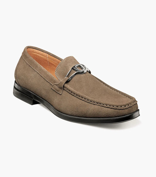 The Stacy Adams Palladian Moc Toe Slip On in Fossil Suede features a metal bit, visible stitching, and a black rubber sole for hybrid dress-casual comfort. Shown here is the men's shoe by STACY ADAMS on a white background.