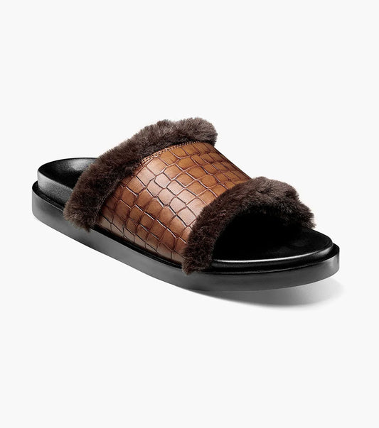 The STACY ADAMS Monty Slide Sandal in Cognac features a brown crocodile print leather strap, dark brown faux fur trim, and black sole, shown on a white background. Style number: 25560-221.