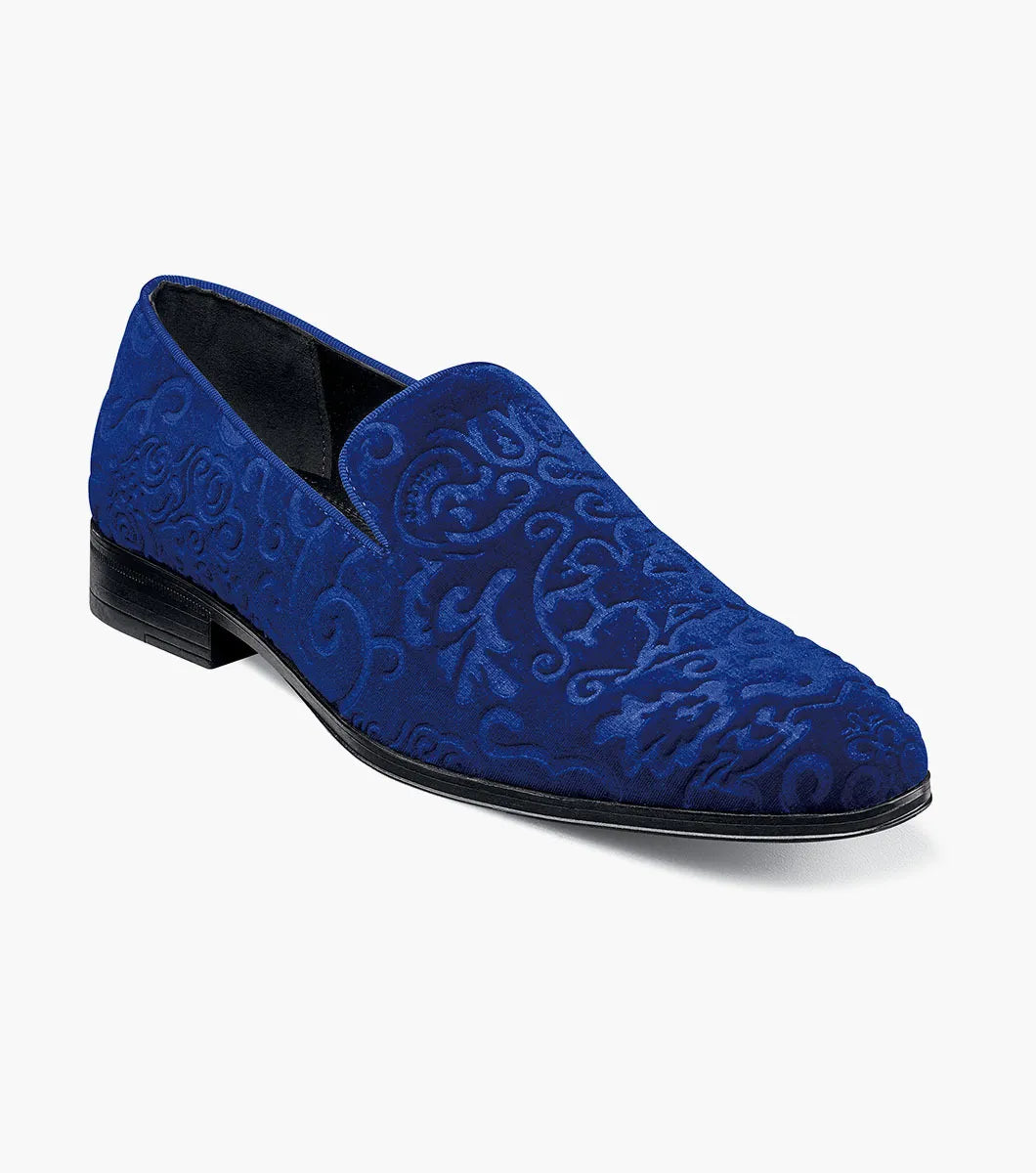 The STACY ADAMS Saunders Debossed Velour Slip On in Royal features a blue velour upper, low heel, intricate swirl embroidery, and a memory foam footbed. Shown in side profile against a white background. Style number: 25581-432.