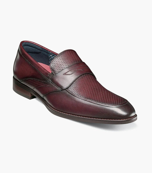The Stacy Adams Karnes Moc Toe Penny Slip On in burgundy features a perforated leather upper, low heel, and rounded toe, shown on a white background.