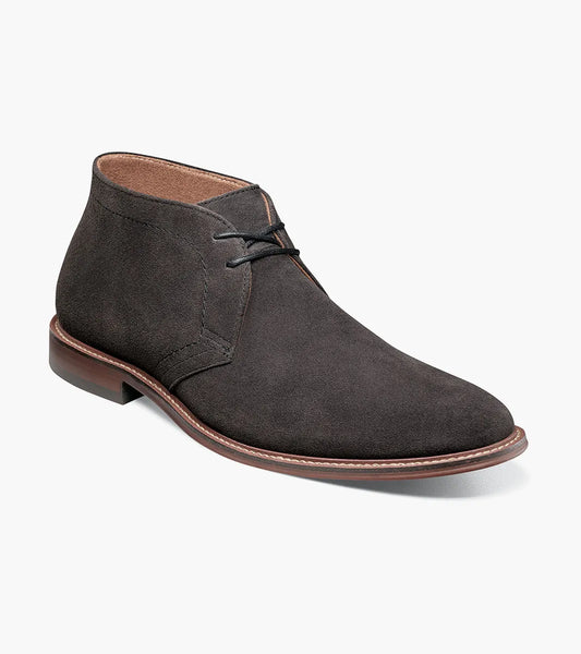 The Stacy Adams Martfield Plain Toe Chukka Boot in dark gray features black laces, a rounded toe, cushioned footbed, and brown sole. Displayed on a white background. Brand: STACY ADAMS.