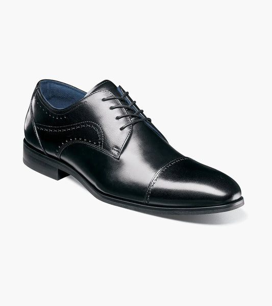 The STACY ADAMS Bryant Cap Toe Oxford (25634-001) is a black leather lace-up dress shoe with FlexZone footbed, cap toe, and subtle side stitching, shown on a white background.