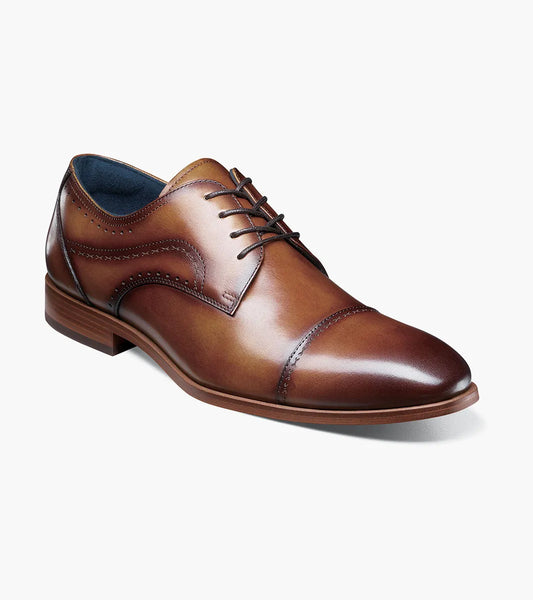 The STACY ADAMS Bryant Cap Toe Oxford (Tan, 25634-240) is a brown burnished leather dress shoe with lace-up closure, anatomical arch support, and a low heel, shown on a white background.