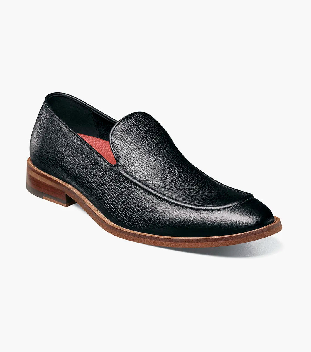 The Stacy Adams Prentice Moc Toe Slip On (25649-007) features black tumbled leather, a textured finish, brown wooden heel, and thin brown sole; shown on a white background.