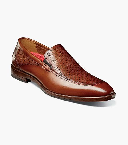 The Stacy Adams Aiden Moc Toe Slip On (Cognac, 25655-221) features genuine brown leather, perforated upper detailing, anatomical arch support, and a low heel, shown on a white background.