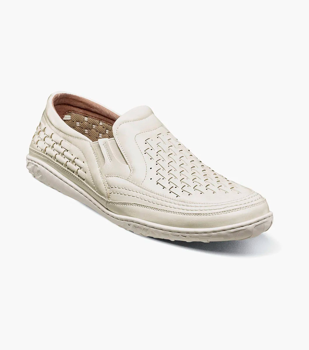 The Stacy Adams Ithaca Moc Toe Slip On in white features woven detailing, a textured sole, elastic side panels for easy wear, and a cushioned memory foam footbed for comfort.