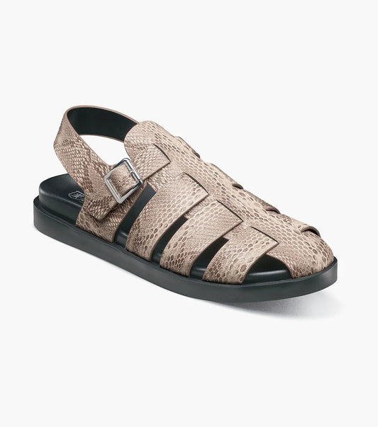 The Stacy Adams Montego Slingback Buckle Sandal (Sand, 25659-269) features a tan snakeskin pattern, closed toe, cutout sides, adjustable buckle strap, black sole, and cushioned EVA midsole on a white background.