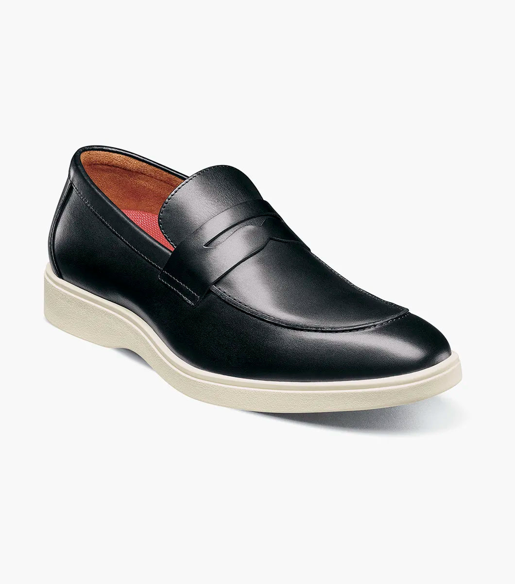 The Stacy Adams Spencer Moc Toe Penny Slip On in black features a leather upper, penny strap, tan lining, and contrasting white rubber sole, showcased on a plain background. Brand: STACY ADAMS. Product code: 25673-001.