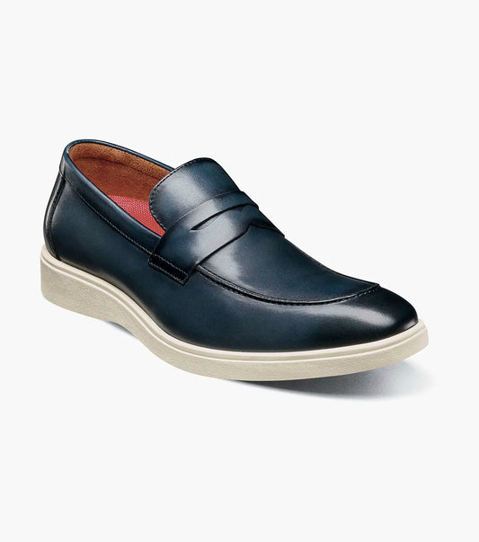 The STACY ADAMS Spencer Moc Toe Penny Slip On in navy (25673-410) features a classic loafer design with a penny strap and white rubber sole, shown angled on a plain white background for timeless style and comfort.