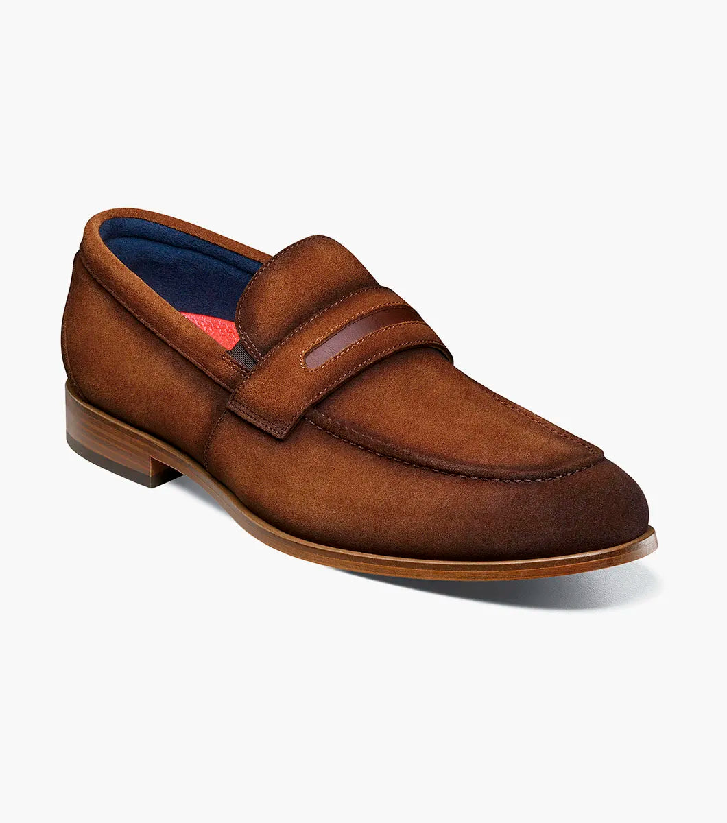 The STACY ADAMS Burke Moc Toe Saddle Slip On in copper (25676-220) features brown suede, a leather strap detail, stitching accents, a low wooden heel, and a cushioned footbed for comfort, shown on a white background.