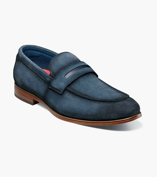 The Stacy Adams Burke Moc Toe Saddle Slip On in navy suede features a penny strap, anatomical arch support, low heel, and brown sole, displayed on a plain white background.