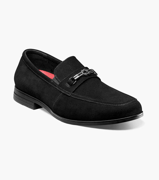 The STACY ADAMS Ravelle Moc Toe Bit Slip On in black suede features a low heel, metal bit on the vamp, anatomical arch support, and a red insole accent, shown against a white background.
