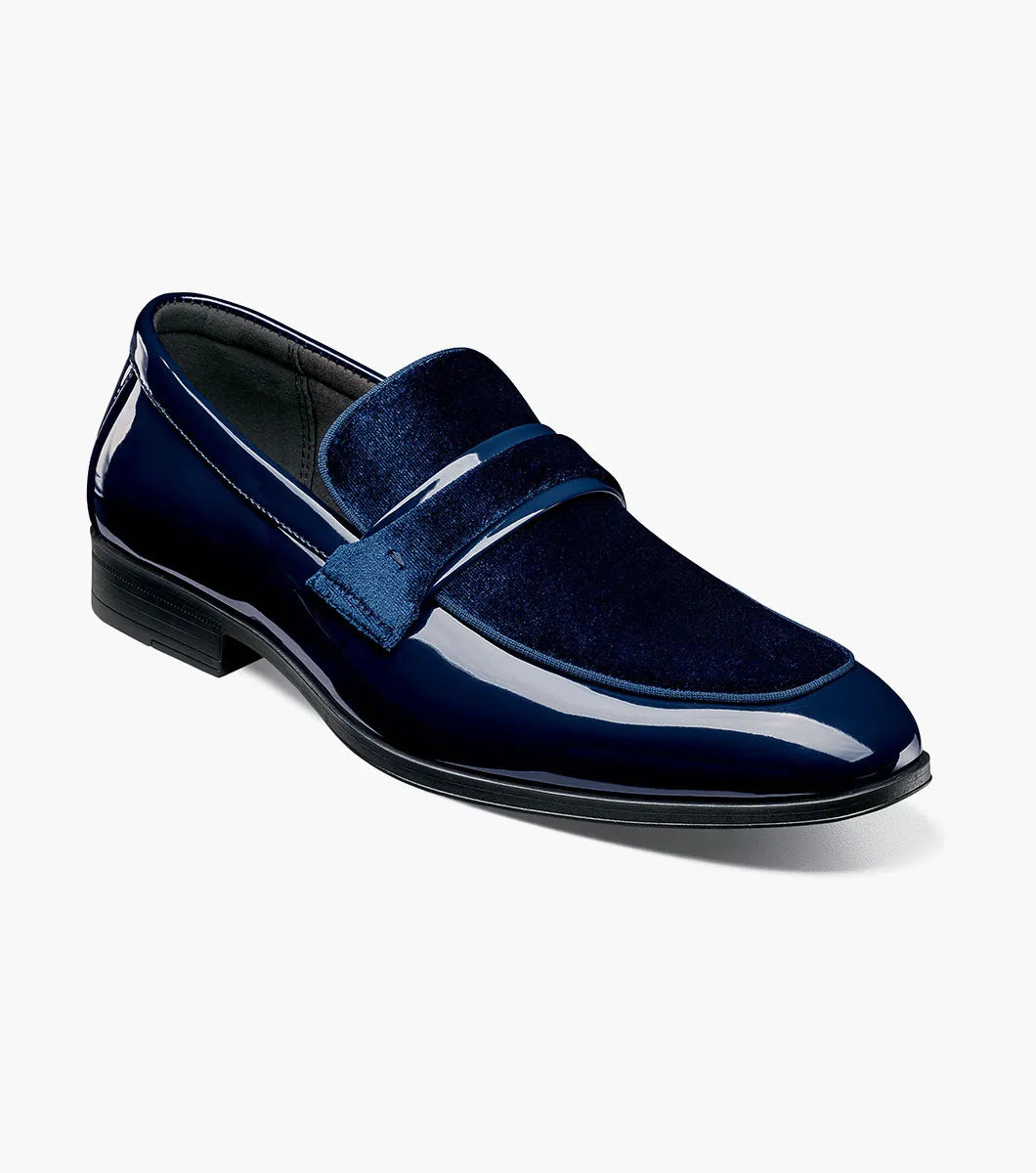 The Stacy Adams Spratley Moc Toe Saddle Slip On (25686-410) features shiny navy blue leather, a matching velour upper, cushioned insole, and low black heel. Displayed solo on a white background.
