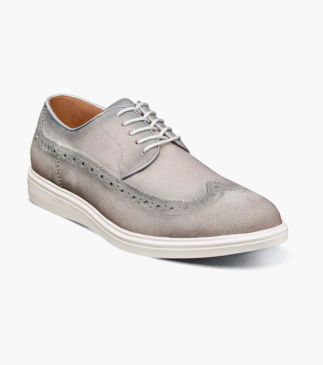 The STACY ADAMS Trudell Wingtip Lace Up in Light Gray (25691-050) features gray suede leather, white laces, and a white rubber sole, shown in a side profile against a plain background.