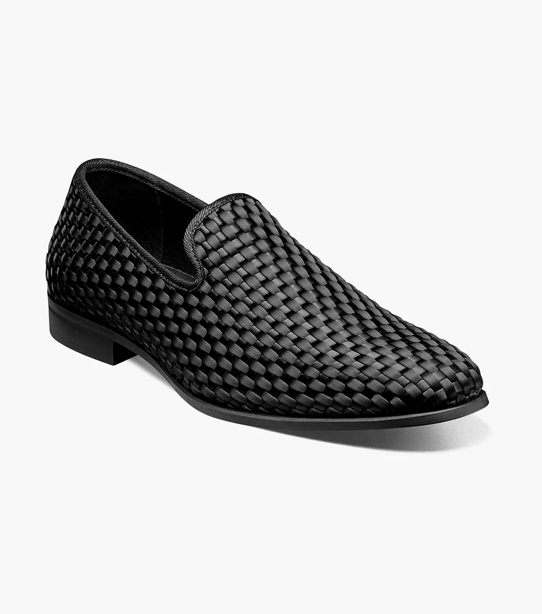 The STACY ADAMS Swenson Woven Slip On in black (25697-001) is a woven leather loafer featuring a low heel and cushioned insole, shown against a white background.