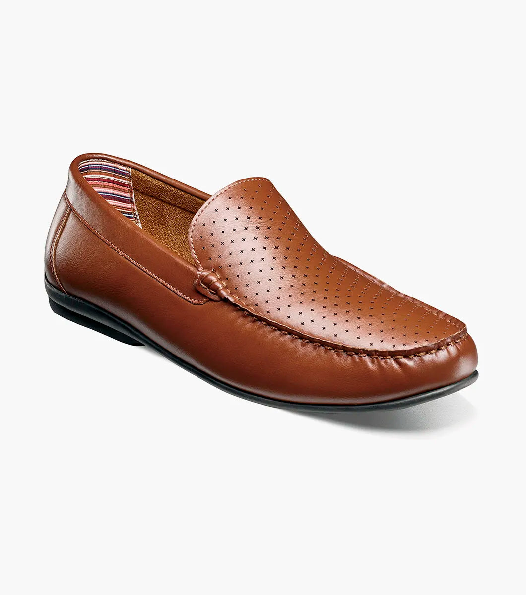 The STACY ADAMS Conroy Moc Toe Perf Slip On in Cognac (25702-221) is a brown leather loafer with a perforated upper, black sole, moccasin-style stitching, and cushioned footbed, shown side profile on a white background.