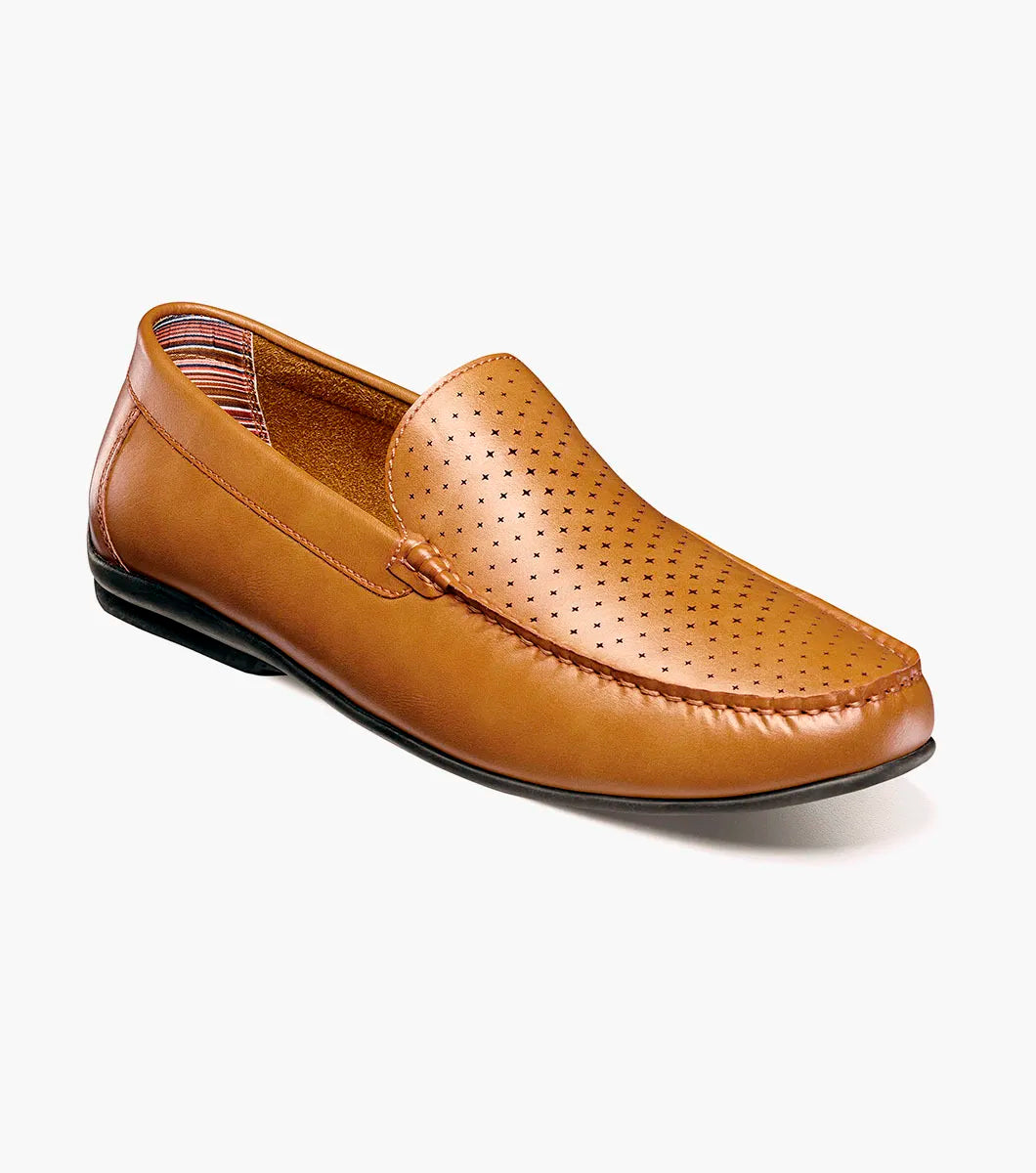 The STACY ADAMS Conroy Moc Toe Perf Slip On (25702-240) in tan features perforated leather uppers, cushioned footbed for all-day comfort, and is shown in a side profile against a white background.