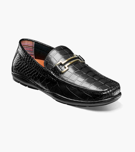 The STACY ADAMS Embrey Moc Toe Bit Slip On (25703-001) is a black leather loafer featuring a crocodile-textured upper and gold metal bit detail, shown in a side profile view.