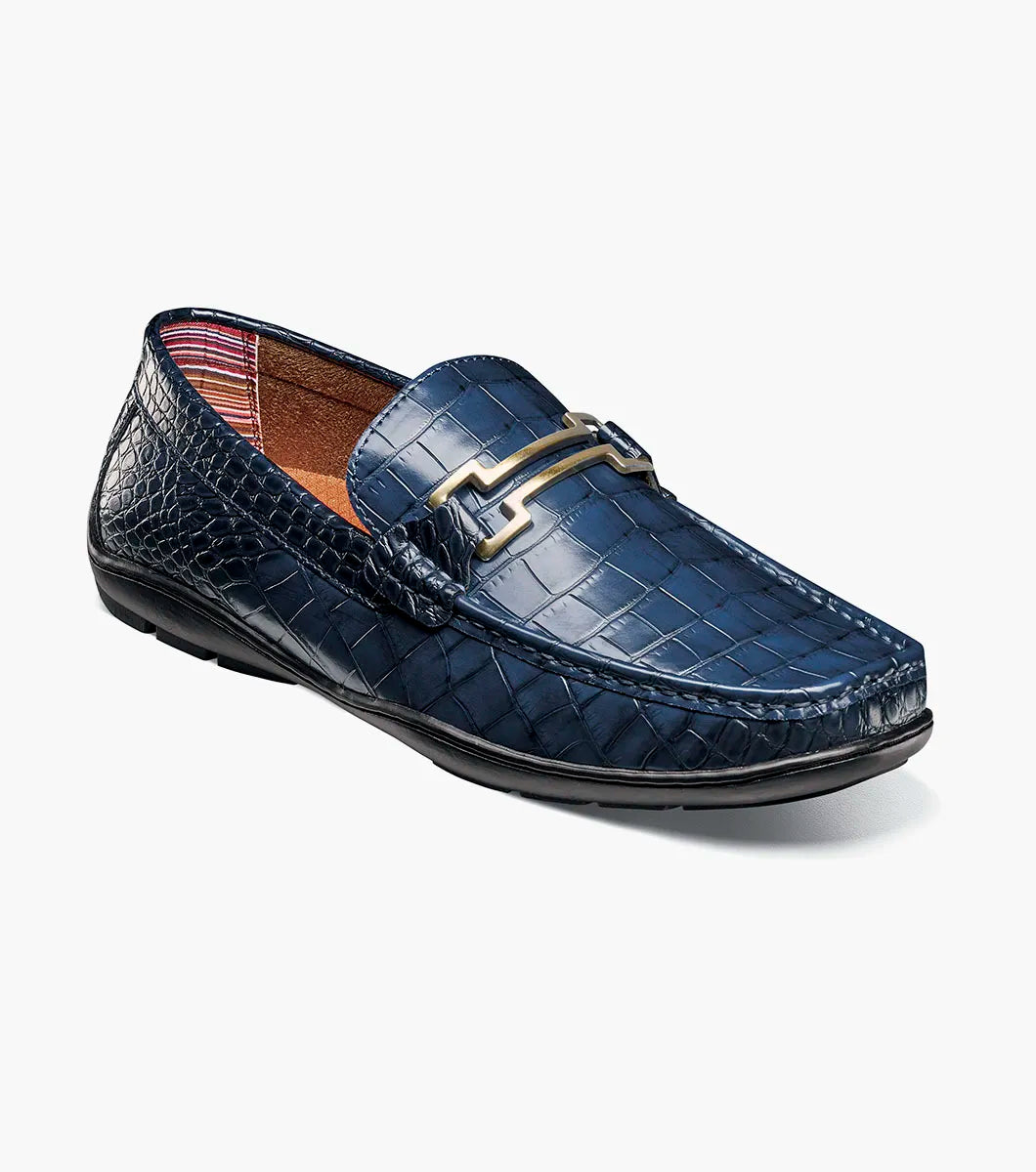 The Stacy Adams Embrey Moc Toe Bit Slip On in navy features crocodile print, a cushioned footbed, black sole, and metal bit detail on the upper, displayed side view on a white background.