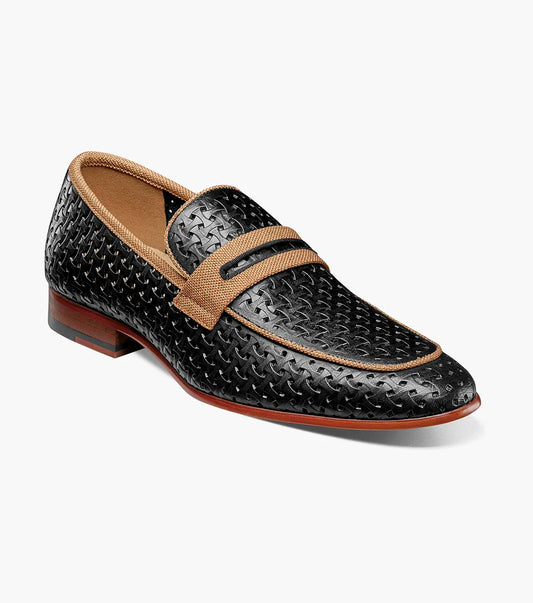 The STACY ADAMS Winstead Moc Toe Saddle Slip On (Black, 25704-001) is a black perforated leather loafer with tan accents, a low heel, brown sole, and FlexZone footbed for comfort, shown in side profile on a white background.