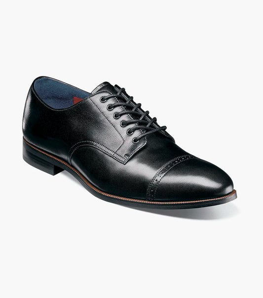 The STACY ADAMS William Cap Toe Oxford (Black, 25719-001) is a black burnished leather dress shoe with laces, a low heel, and comfortable stride, shown in profile against a white background.