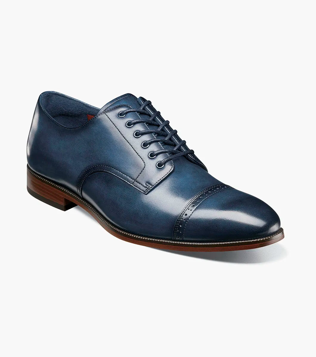 The STACY ADAMS William Cap Toe Oxford (25719-410) in navy leather features decorative perforations, a FlexZone footbed for comfort, and a durable rubber outsole. Shown in side profile on a white background.