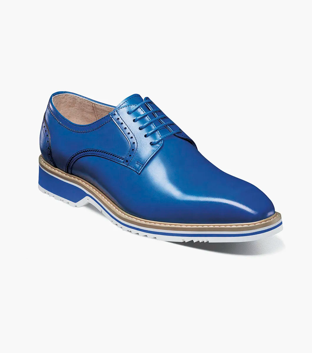 The Stacy Adams Barringer Plain Toe Oxford in blue features a leather upper with laces, a tan and white layered sole, durable rubber outsole, and subtle stitching details, shown in side view against a white background.