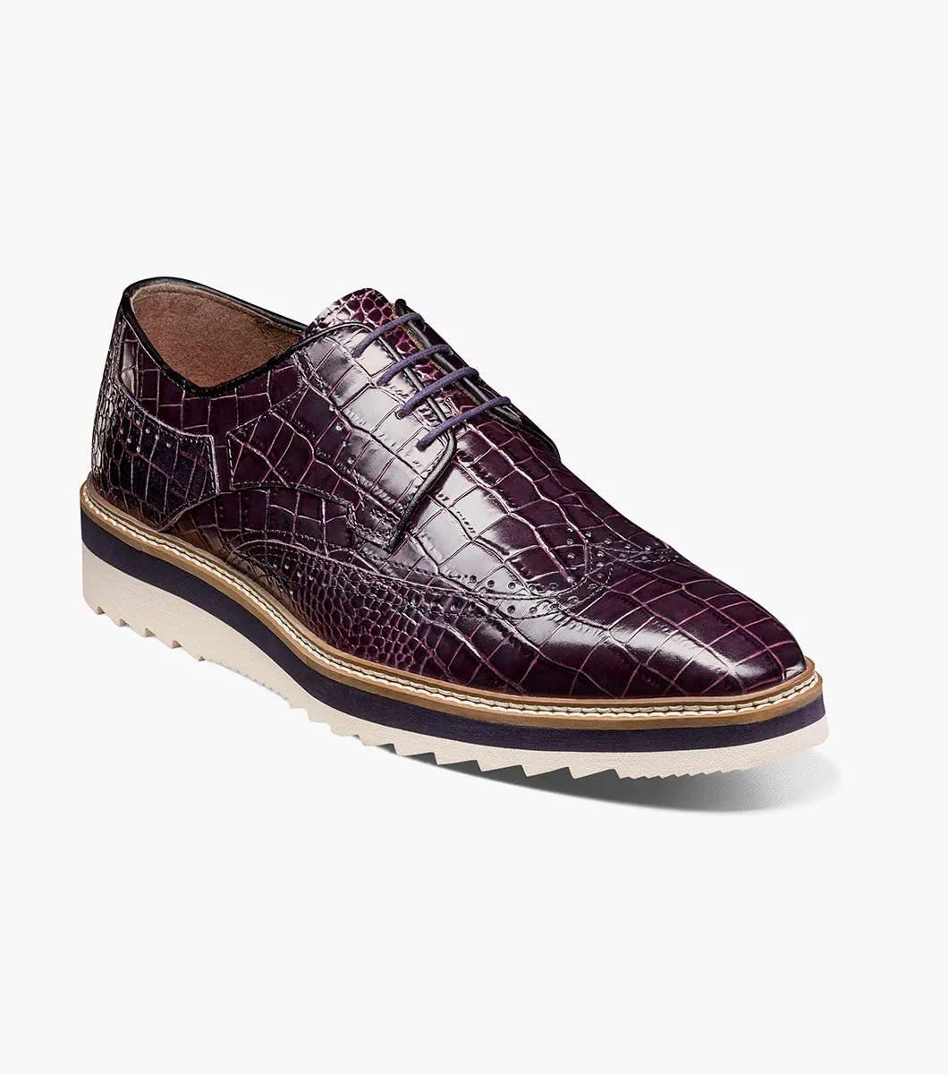 The Stacy Adams Alario Wingtip Oxford in purple (25725-542) features crocodile print leather, a lace-up design, contrasting sole, and textured outsole, shown on a white background.
