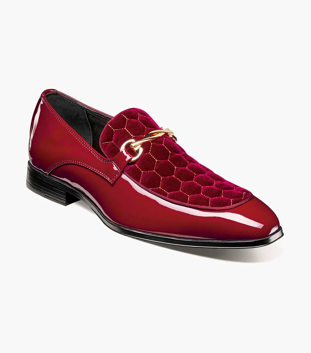 The STACY ADAMS Sprague Moc Toe Bit Slip On in burgundy (25732-601) features a glossy finish, gold buckle, hexagonal velvet-patterned upper, and a memory foam insole, shown against a white background.