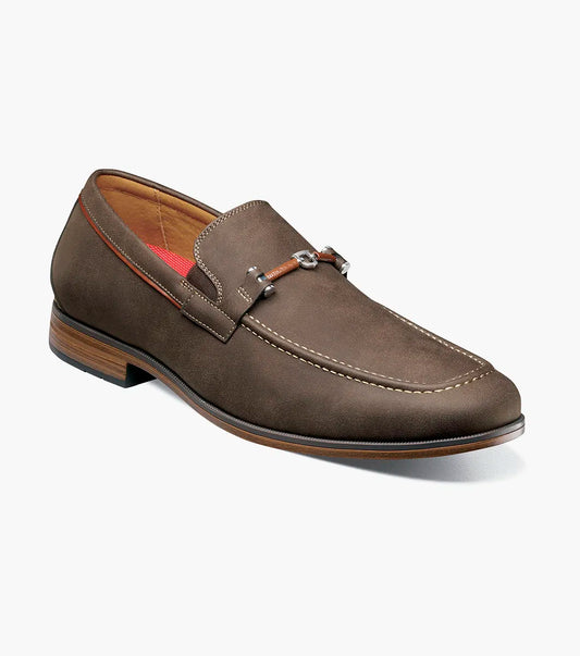 The Stacy Adams Richardson Moc Toe Bit Slip On (Brown, 25746-200) features suede, a metal bit detail, light stitching, red lining, a low wooden heel, and a cushioned RedZone footbed for all-day comfort.