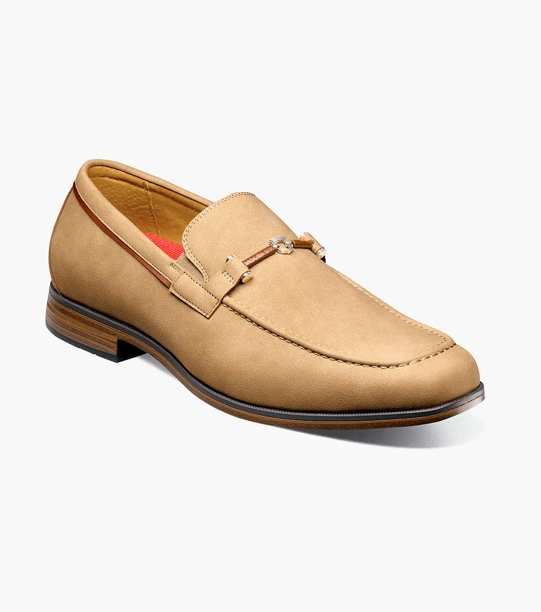 The STACY ADAMS Richardson Moc Toe Bit Slip On (Khaki, 25746-274) is a men's loafer featuring a metal bit detail, low wooden heel, and cushioned RedZone footbed, displayed on a white background.
