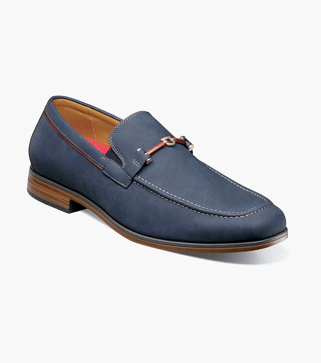 The STACY ADAMS Richardson Moc Toe Bit Slip On in navy features a leather upper with white stitching, metal bit detail, RedZone footbed, brown sole, and red lining, shown on a white background.
