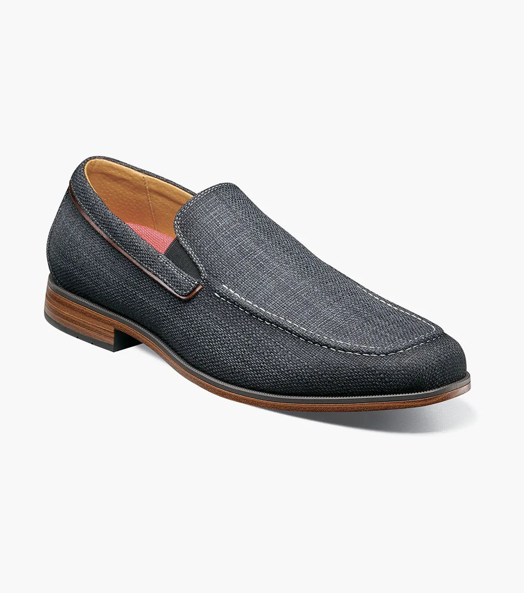 The Stacy Adams Ridgely Moc Toe Slip On in charcoal features visible stitching, a low wooden heel, comfy footbed, and tan lining. Shown against a white background, this casual loafer is perfect for everyday wear.
