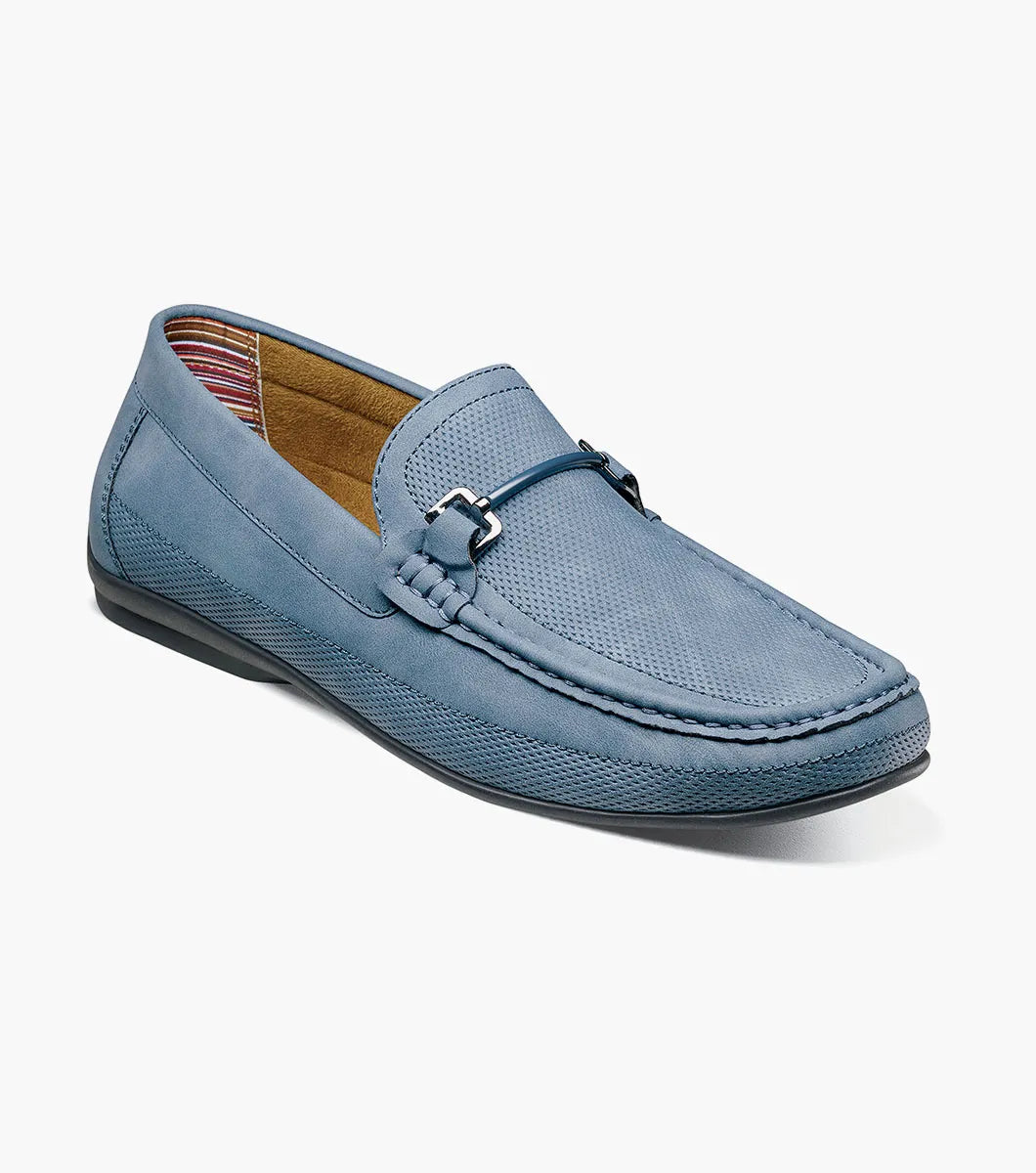 The STACY ADAMS Colton Moc Toe Bit Slip On (Navy, 25760-410) features a cushioned footbed, metal bit detail, moc toe stitching, and a flat black sole, shown on a white background.
