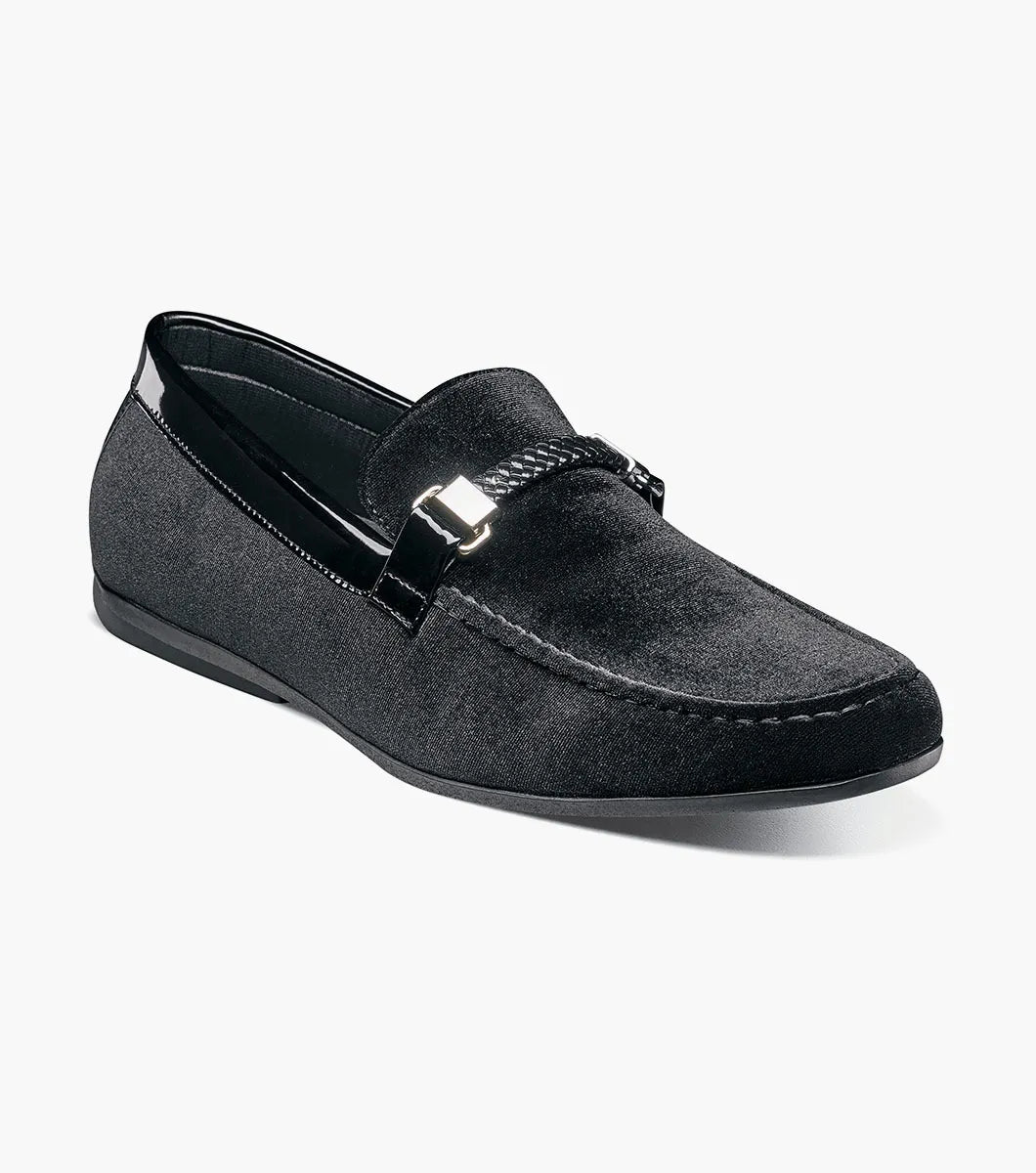 The Stacy Adams Sheridan Moc Toe Bit Slip On (black, 25761-001) is a sleek black suede dress shoe with braided detail and metal accent, low heel, and satin-lined interior for comfort.