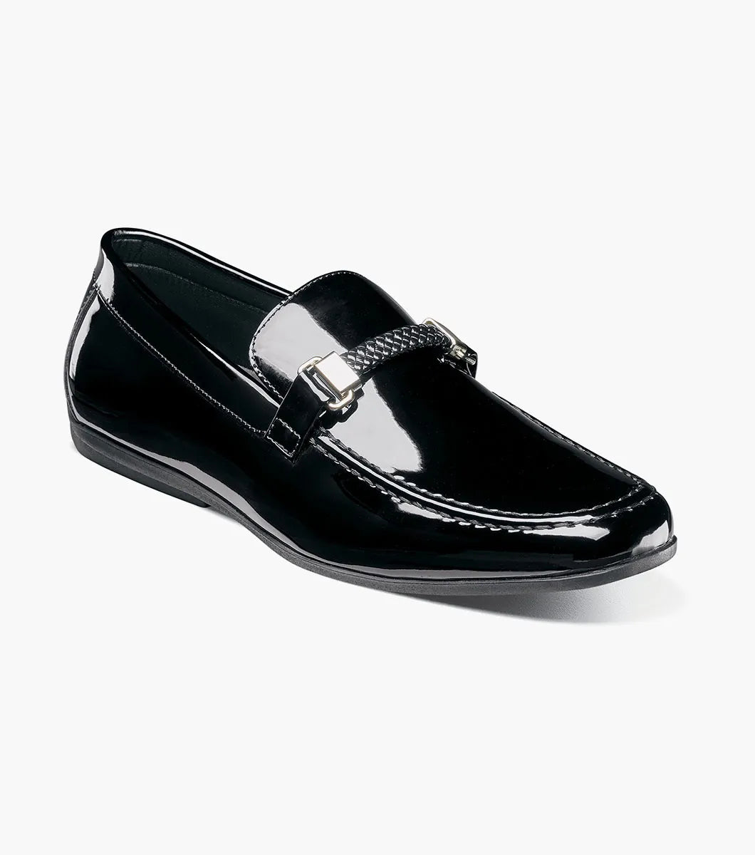 The STACY ADAMS Sheridan Moc Toe Bit Slip On (Black Patent, 25761-004) is shown: a single low-heeled loafer with black patent leather, braided strap detail, and classic styling on a plain white background.