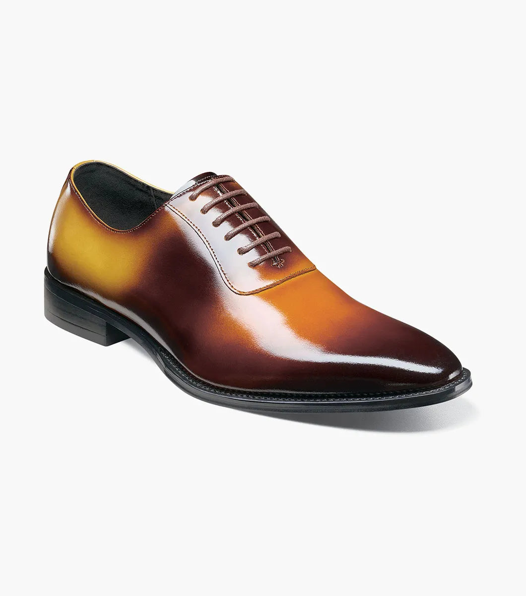 The STACY ADAMS Shaffer Plain Toe Oxford in Cognac Multi (25763-229) features calf leather with a brown-yellow gradient, laces, a low heel, memory foam insole, and polished finish, displayed on a white background.