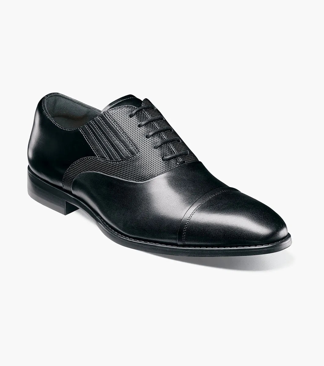 The STACY ADAMS Lucas Cap Toe Oxford (25766-001) is a black leather men's dress shoe with textured side panels, black laces, and a supportive RedZone footbed, shown on a plain white background.